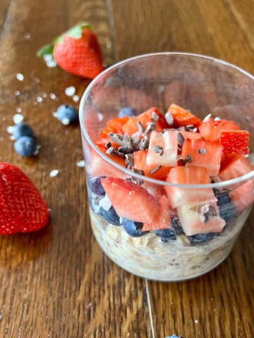 classic overnight oats in a glass with strawberries and blueberries