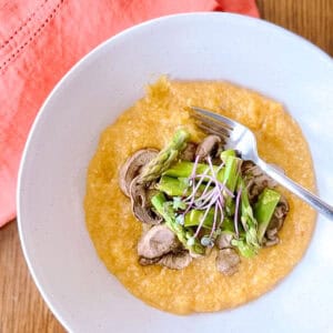 bowl of harissa polenta with mushrooms and asparagus with fork