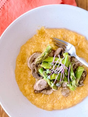 bowl of harissa polenta with mushrooms and asparagus with fork