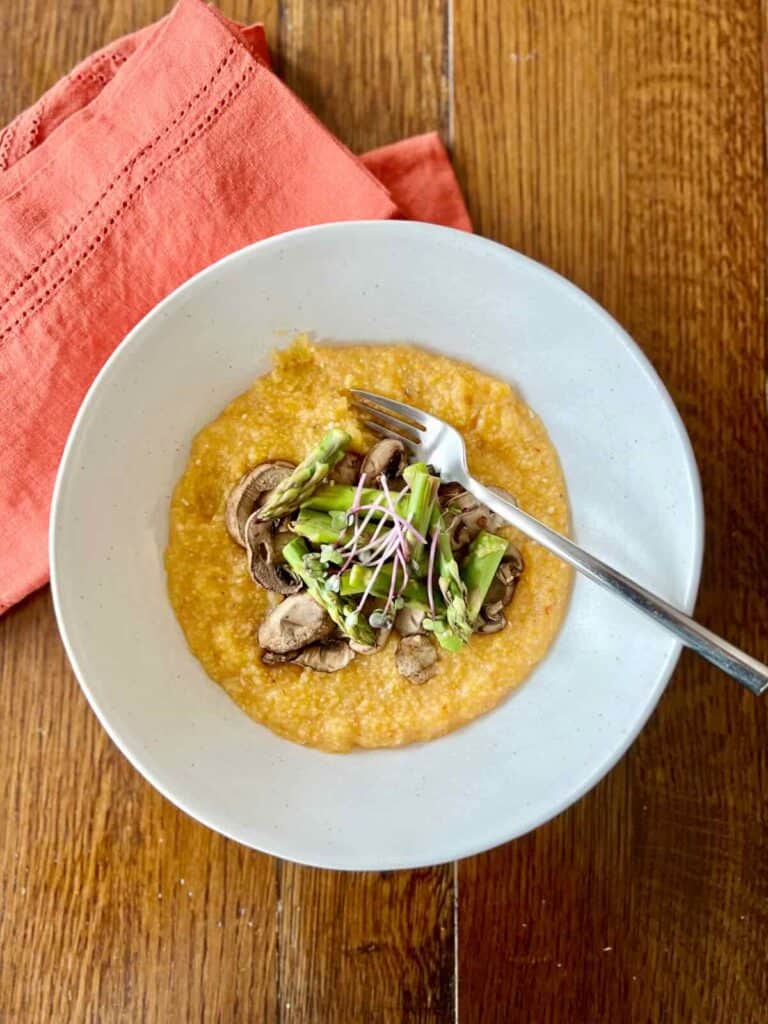 bowl of harissa polenta with mushrooms and asparagus with fork