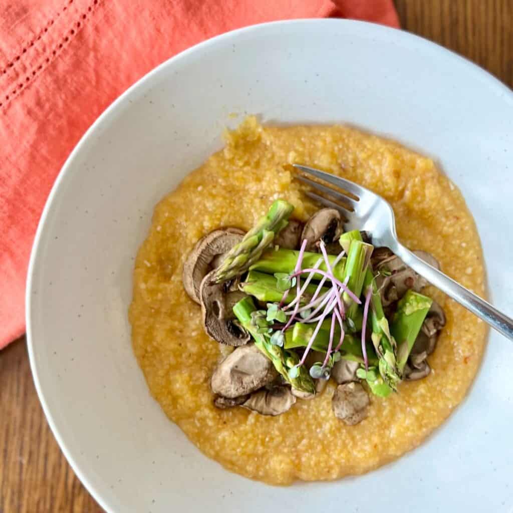 close up overhead of bowl of harissa polenta with mushrooms and asparagus