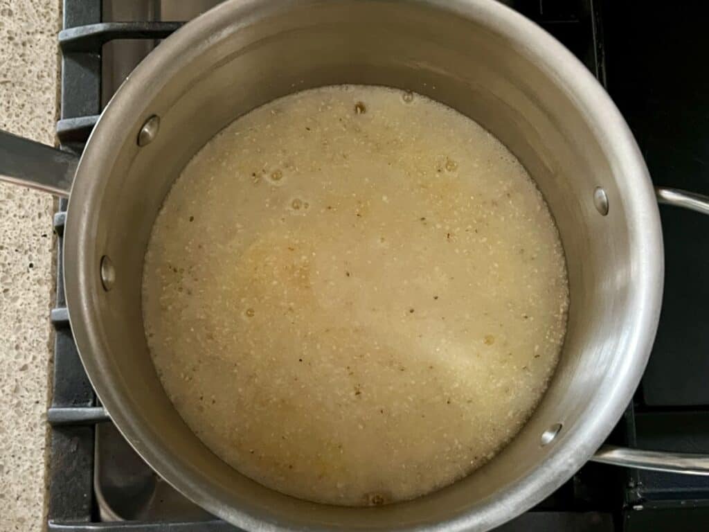 stainless steel pot containing water and uncooked polenta on a stove