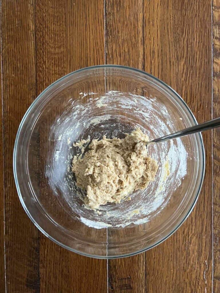 overhead view of glass bowl containing wet and dry ingredients mixed 