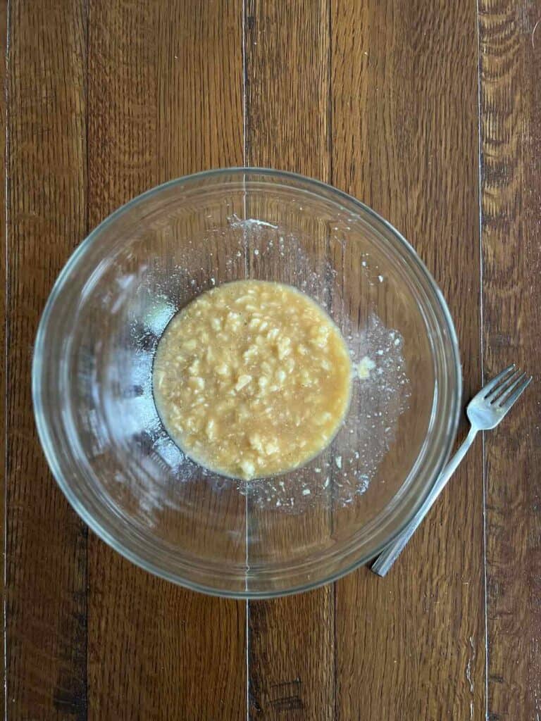 overhead view of glass bowl containing mixed wet ingredients, with a fork to the side