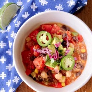 bowl of zesty quinoa chili garnished with sliced jalapeños and red cabbage