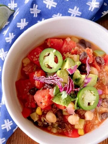 bowl of zesty quinoa chili garnished with sliced jalapeños and red cabbage