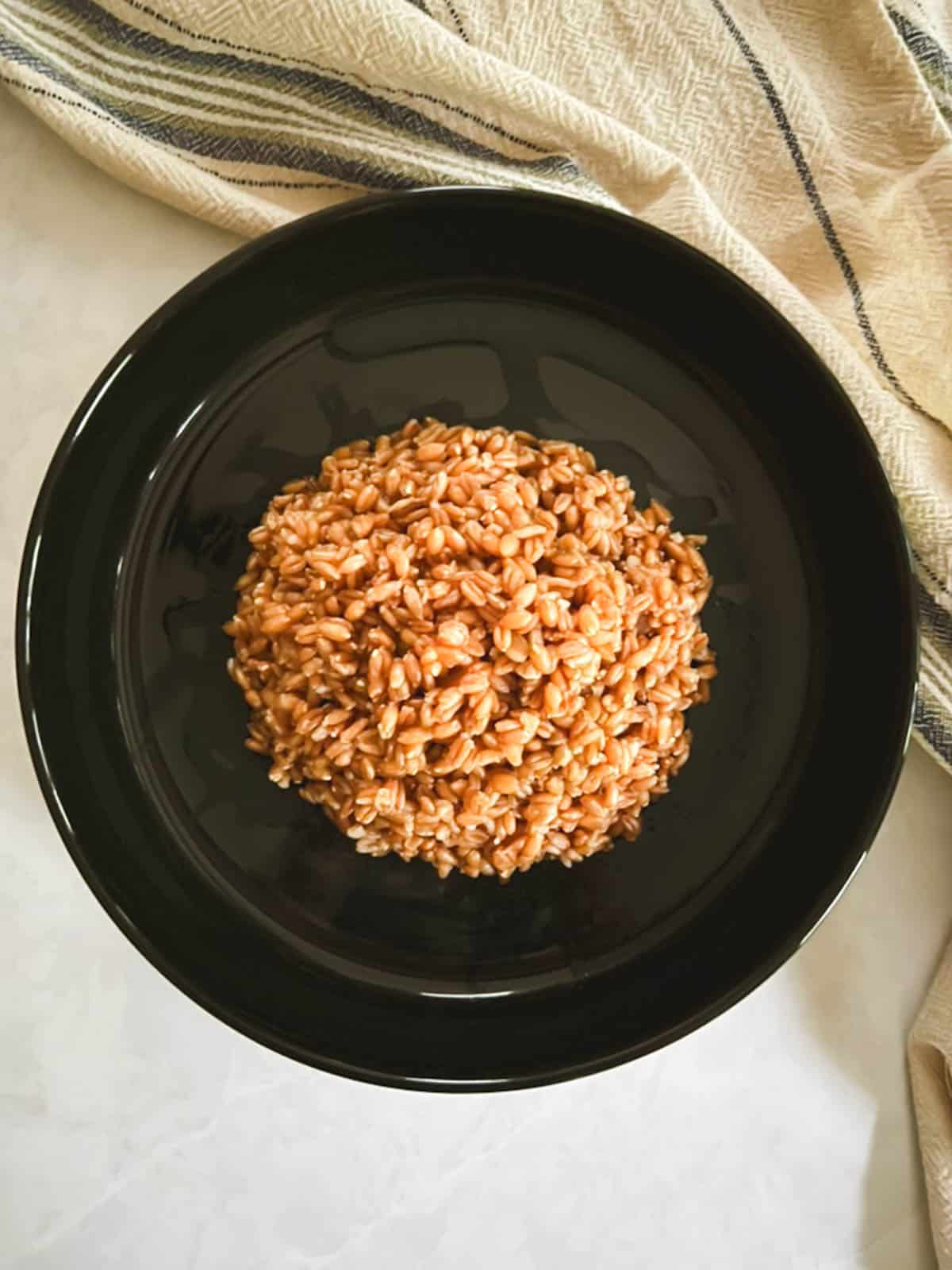 overhead view of plate of cooked farro with towel in background