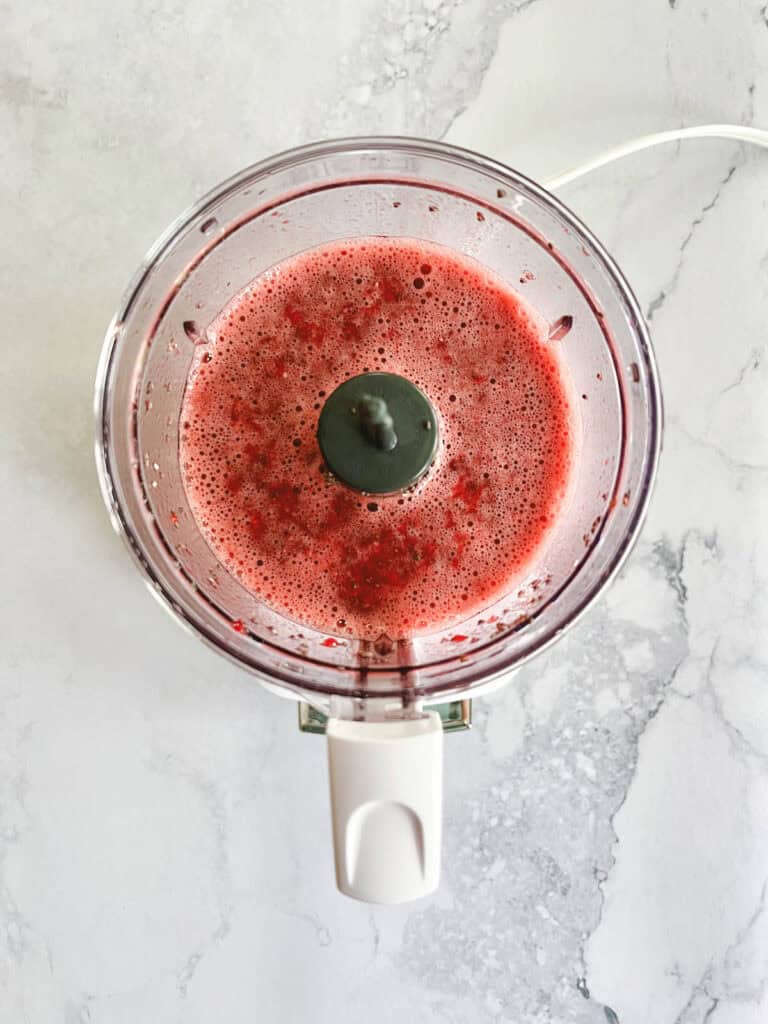 food processor with blended ingredients for raspberry chia pudding