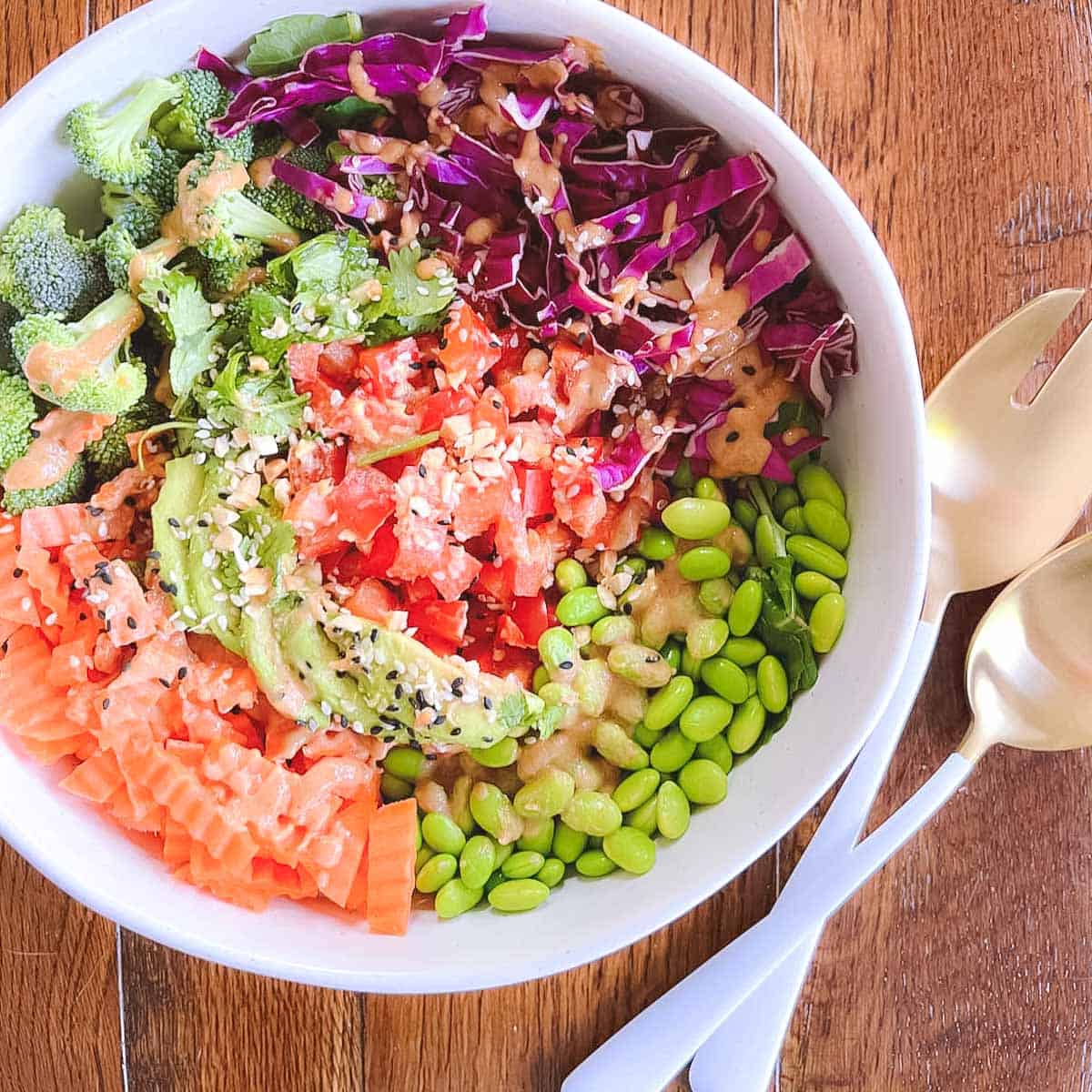 bowl of easy rainbow crunch edamame salad with serving tongs