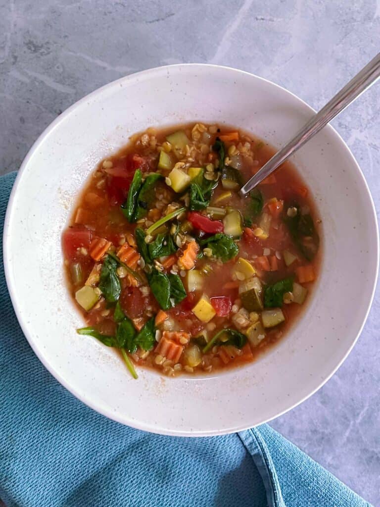 bowl of simple red lentil minestrone soup with spoon