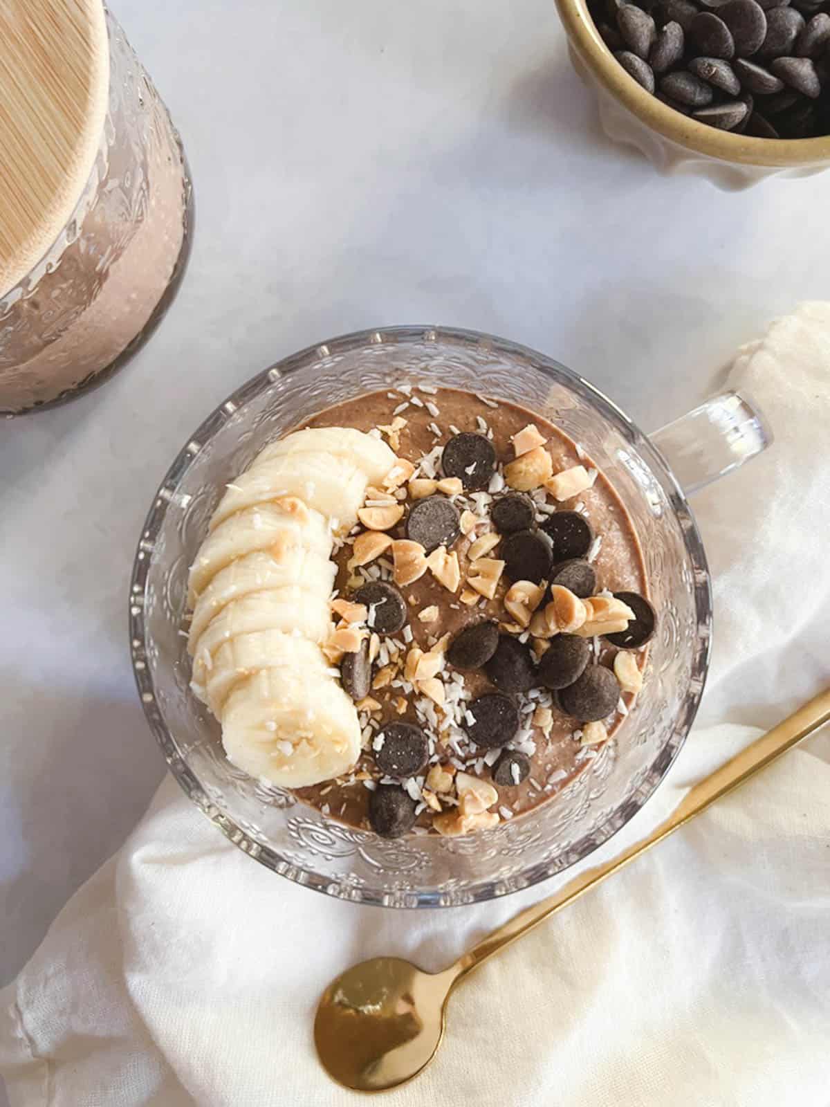 serving of creamy blended chocolate peanut butter overnight oats with toppings and gold spoon