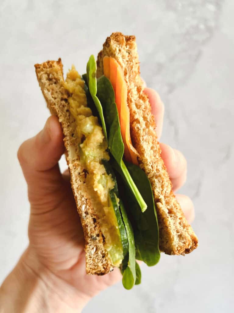 hand holding half of a vegan tuna salad sandwich