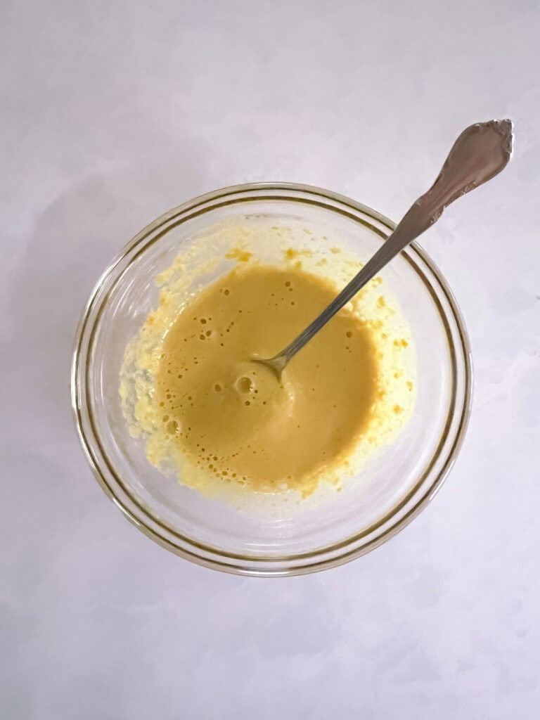 small bowl with combined nutritional yeast and nondairy milk and spoon