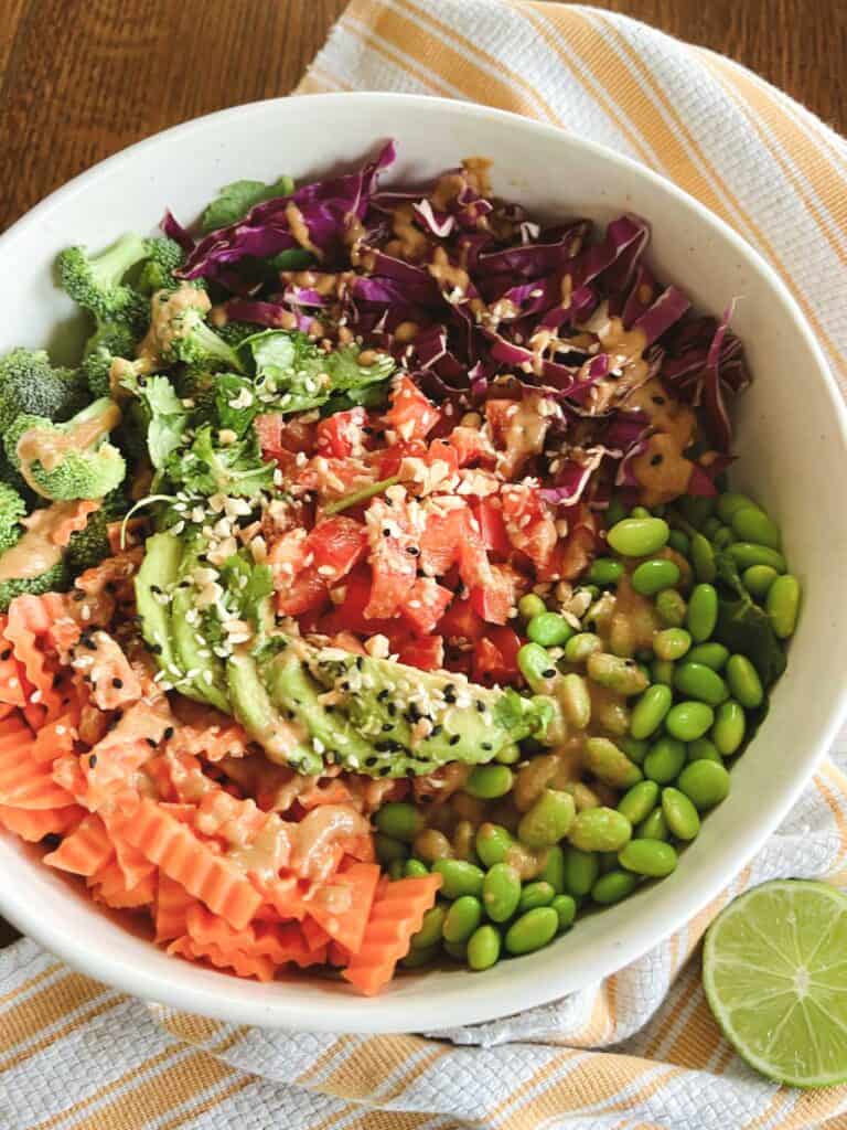 close up of rainbow crunch edamame salad with garnishes and a sliced lime on the side