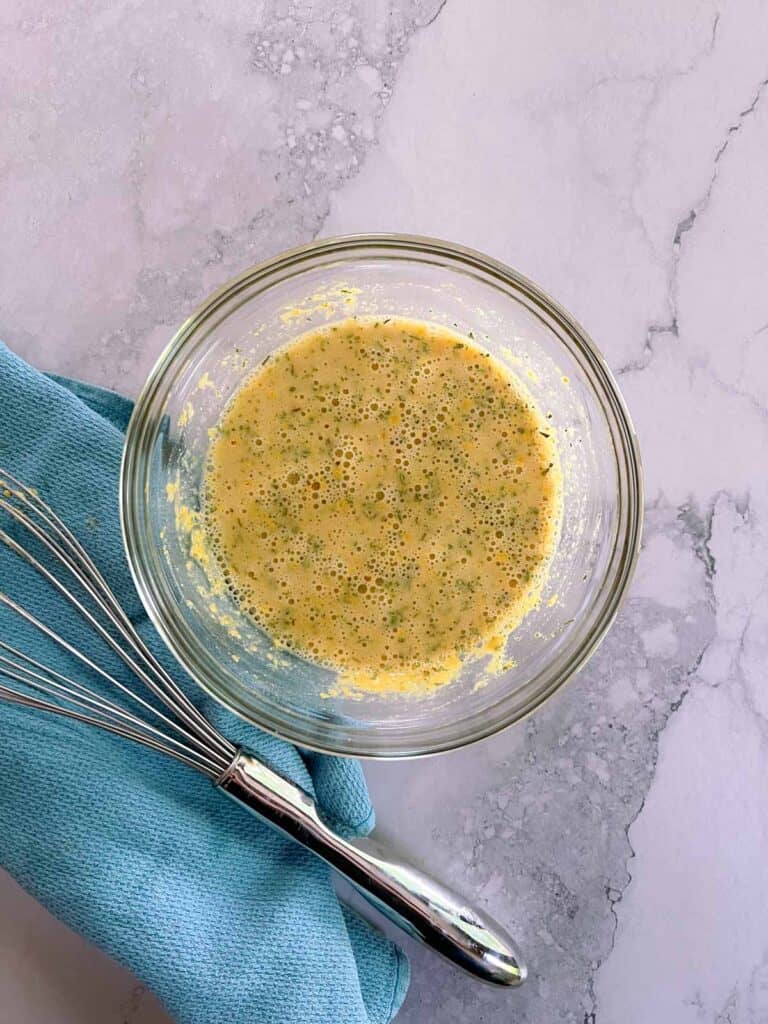 finished sauce in a small bowl with a whisk and towel to the side