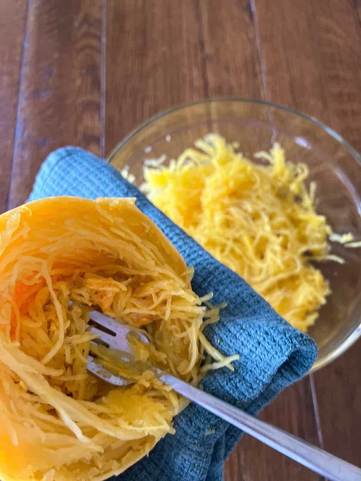 fork removing strands from half a spaghetti squash