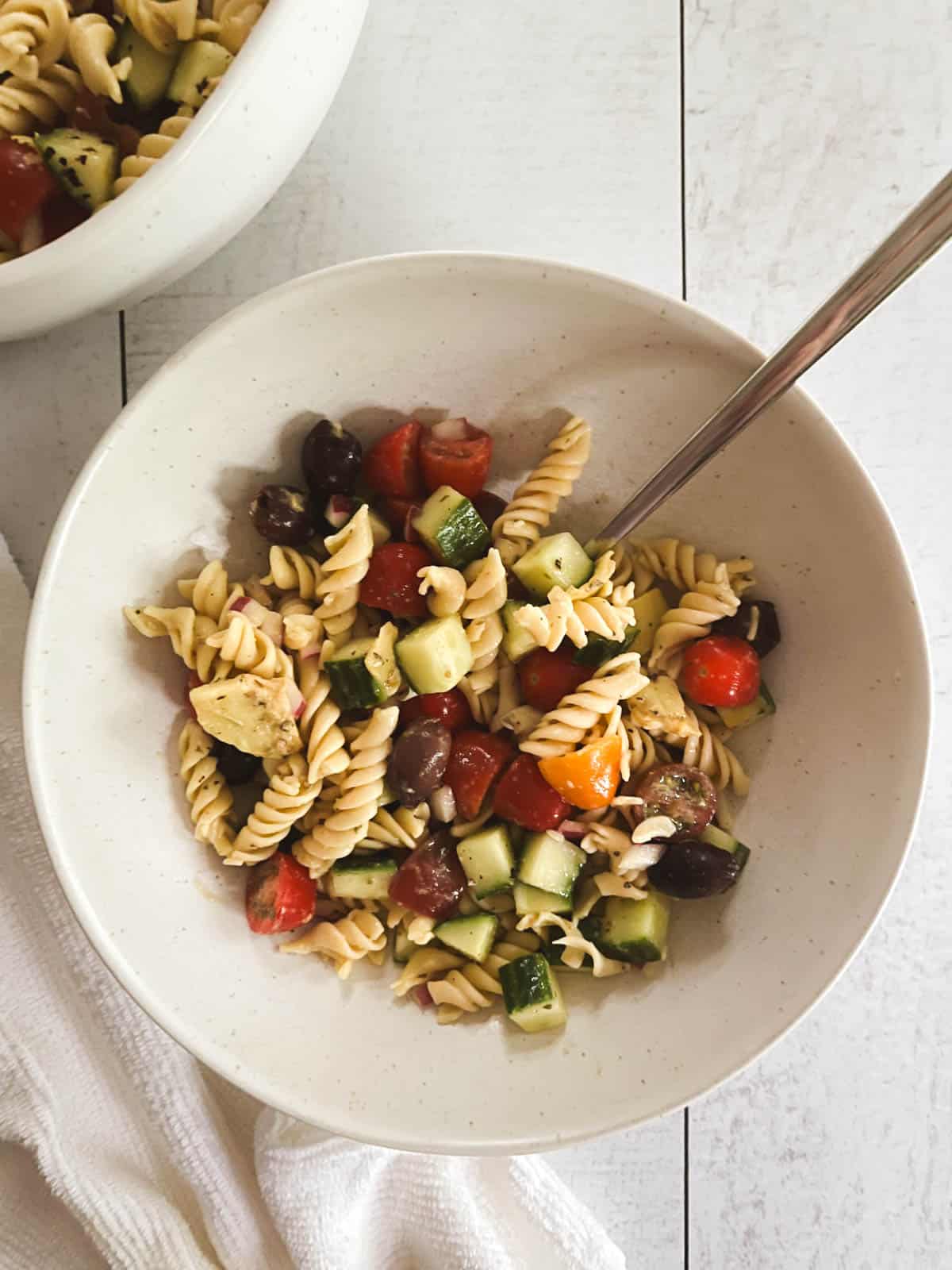 overhead of small bowl of healthy vegan pasta salad with spoon in it and napkin tucked underneath