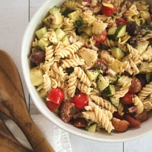 close up of oil-free healthy vegan pasta salad in a bowl with wooden serving tongs