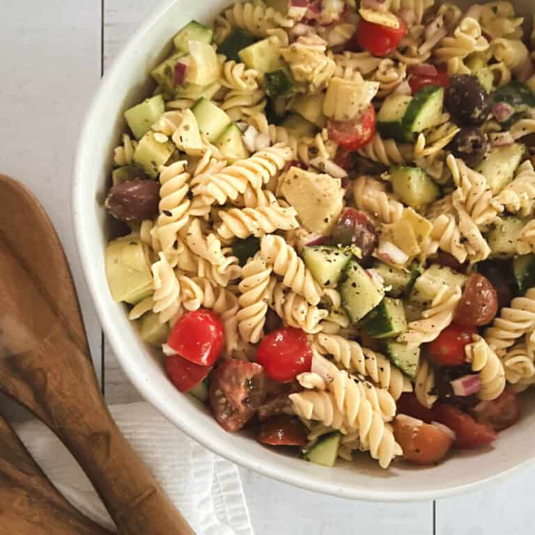 close up of oil-free healthy vegan pasta salad in a bowl with wooden serving tongs