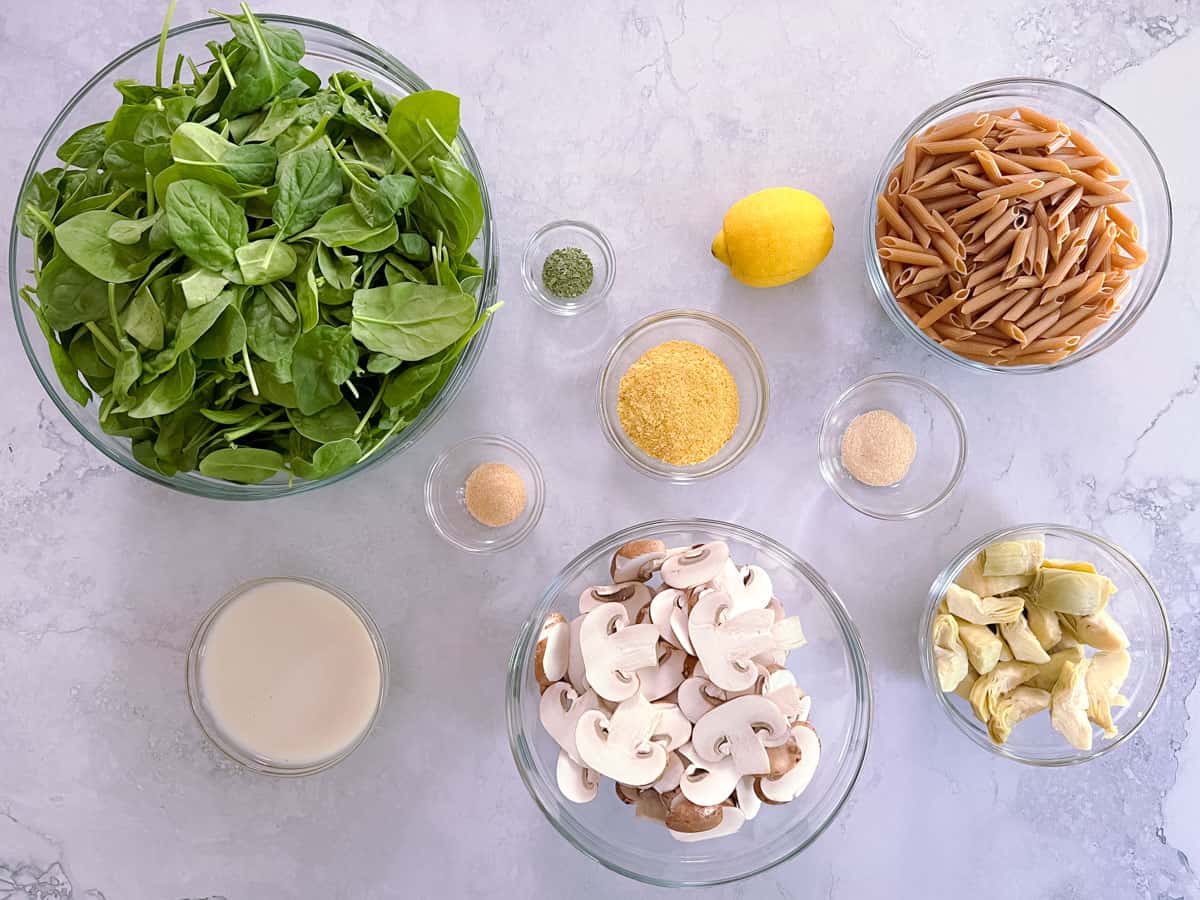 bowls of ingredients for spinach, mushroom, and artichoke pasta