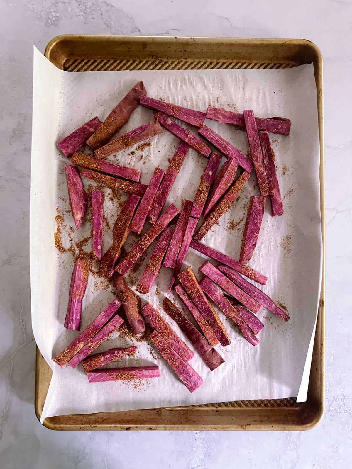 baking sheet with Tex-Mex seasoned purple sweet potato fries arranged on parchment paper