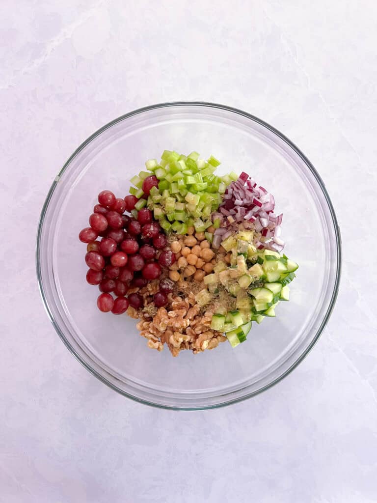 bowl containing unmixed Mediterranean salad ingredients with dressing