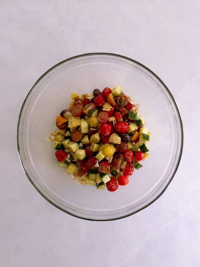 bowl containing mixed salad ingredients coated with dressing