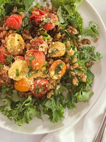 close up of a plate with farro and kale salad with blistered tomatoes