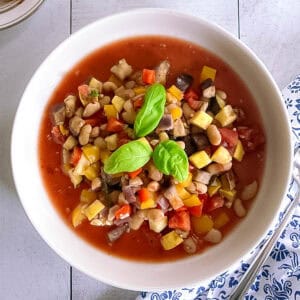 bowl of slow cooker ratatouille with white beans garnished with basil leaves