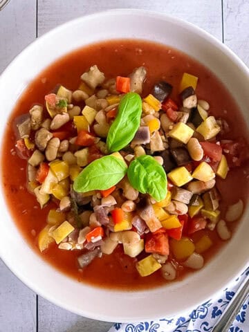 bowl of slow cooker ratatouille with white beans garnished with basil leaves