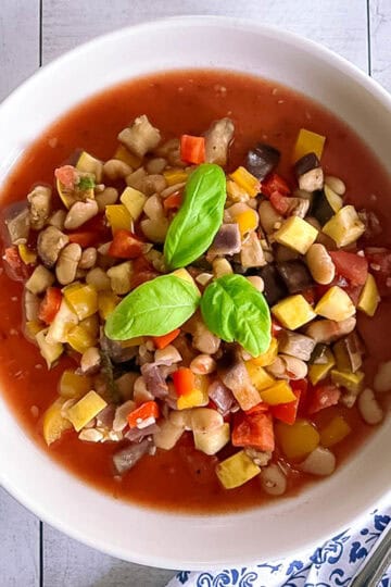 bowl of slow cooker ratatouille with white beans garnished with basil leaves