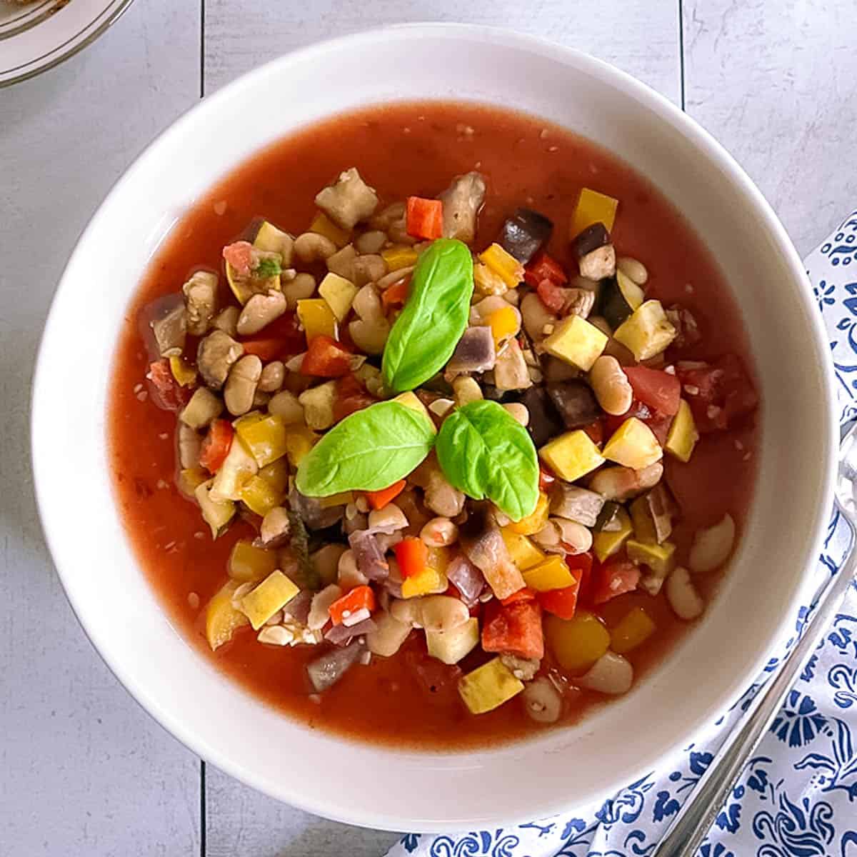 white bowl of slow cooker ratatouille garnished with basil leaves