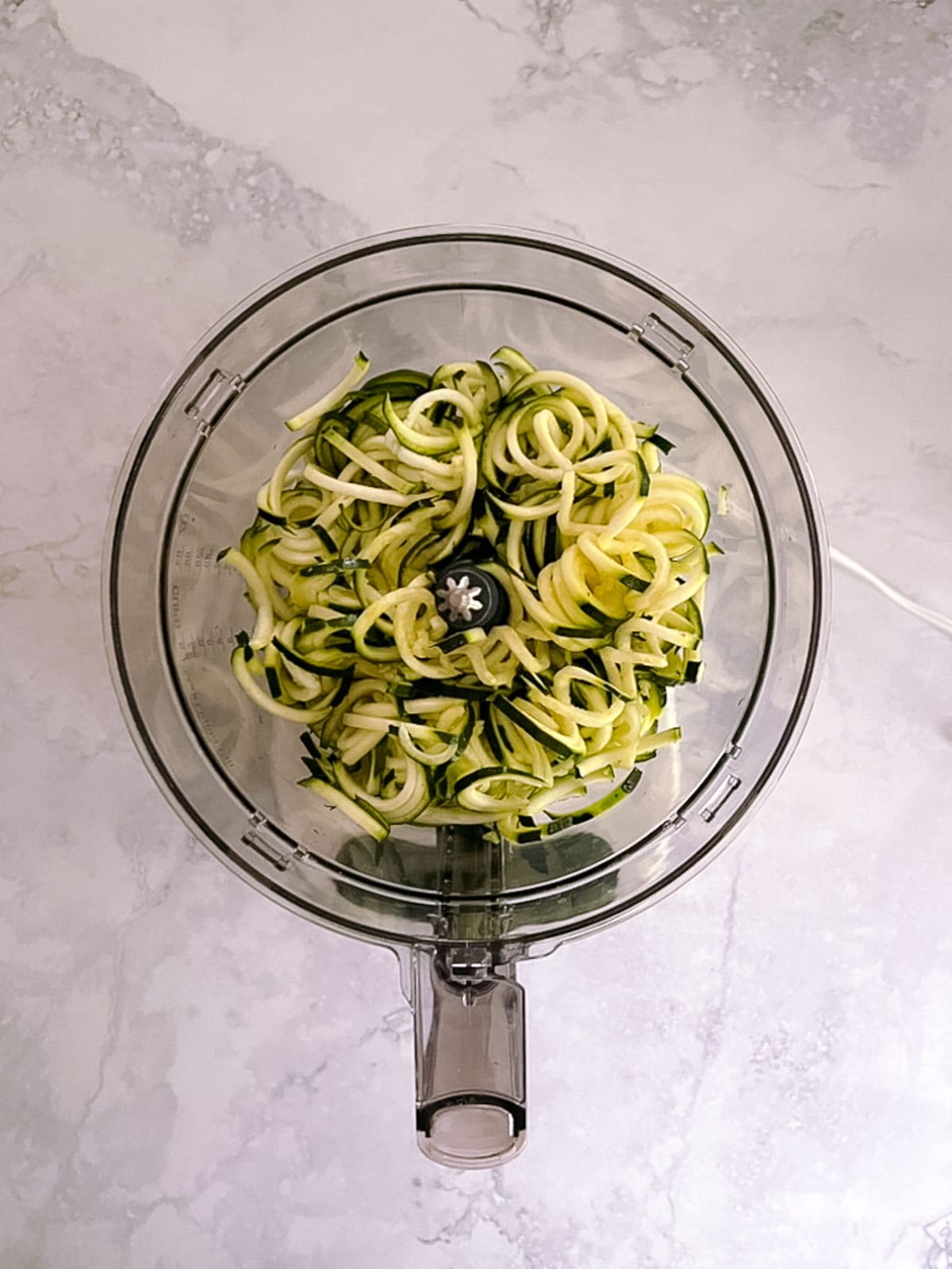 overhead of spiralized zucchini in a food processor