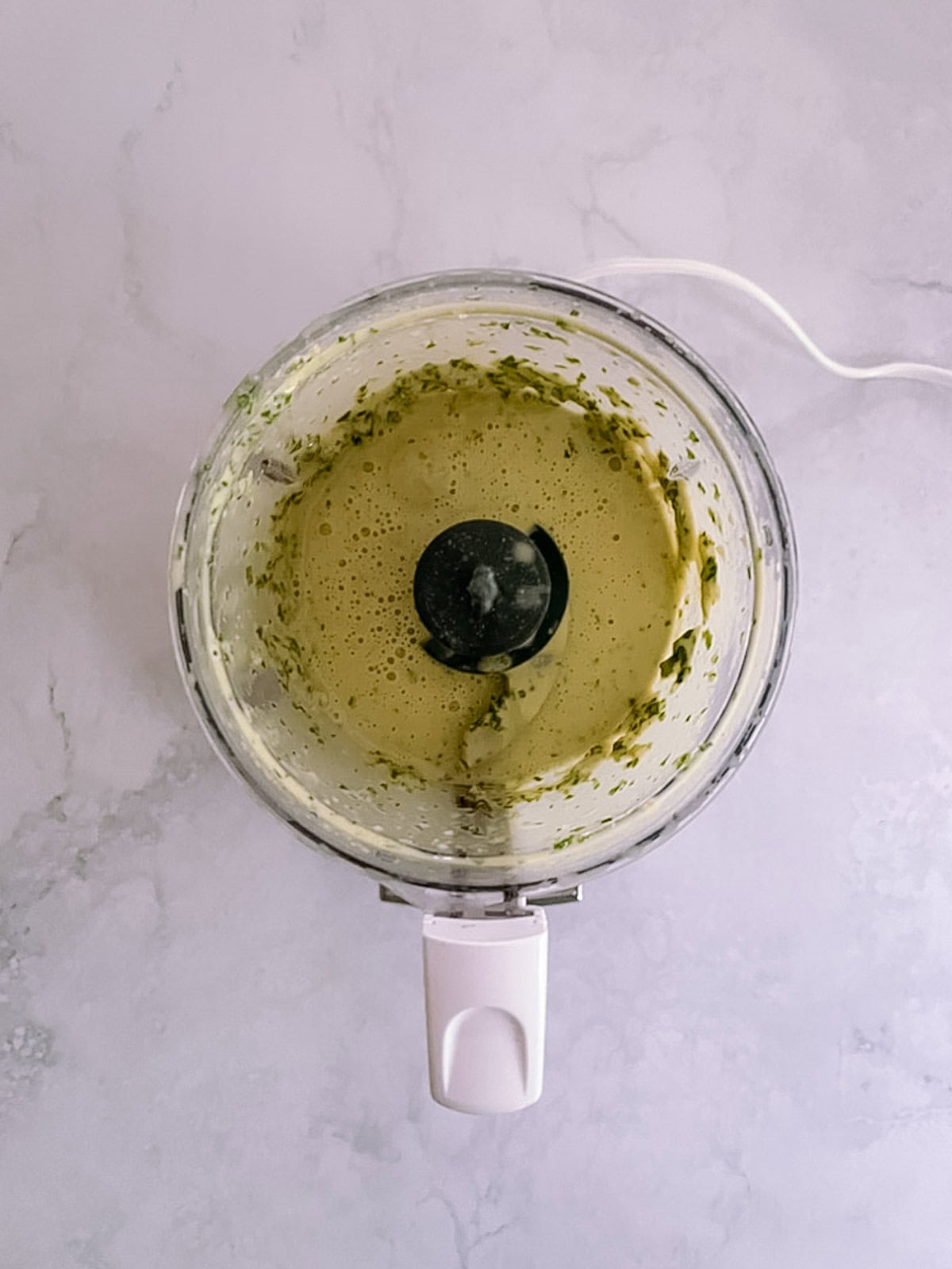 overhead of mini food processor with blended sauce ingredients