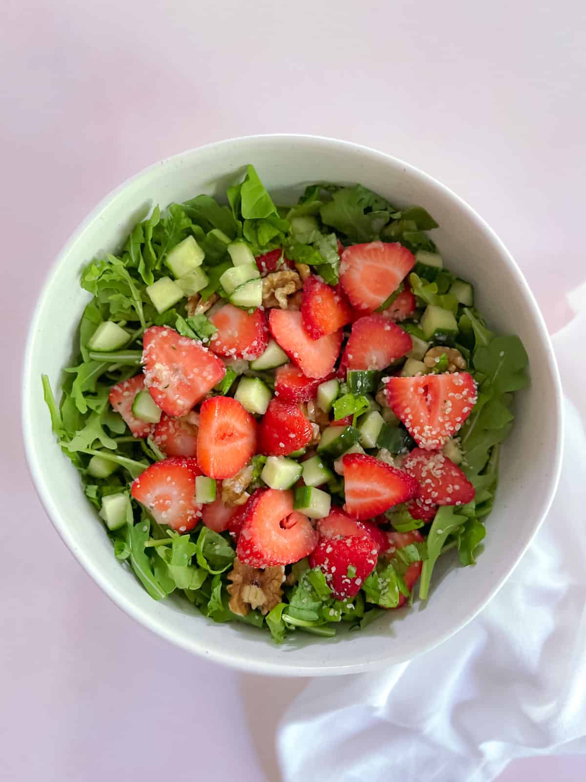 overhead shot of bowl of strawberry basil salad with champagne vinaigrette with cloth napkin