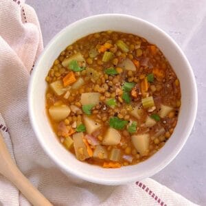 bowl of essential instant pot lentil soup with cloth napkin and wooden spoon