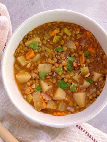 bowl of essential instant pot lentil soup with cloth napkin and wooden spoon