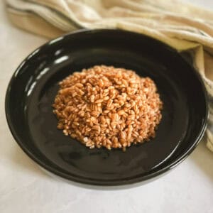 closeup of serving of cooked farro on a plate with a towel in the background