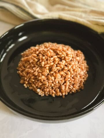 closeup of serving of cooked farro on a plate with a towel in the background