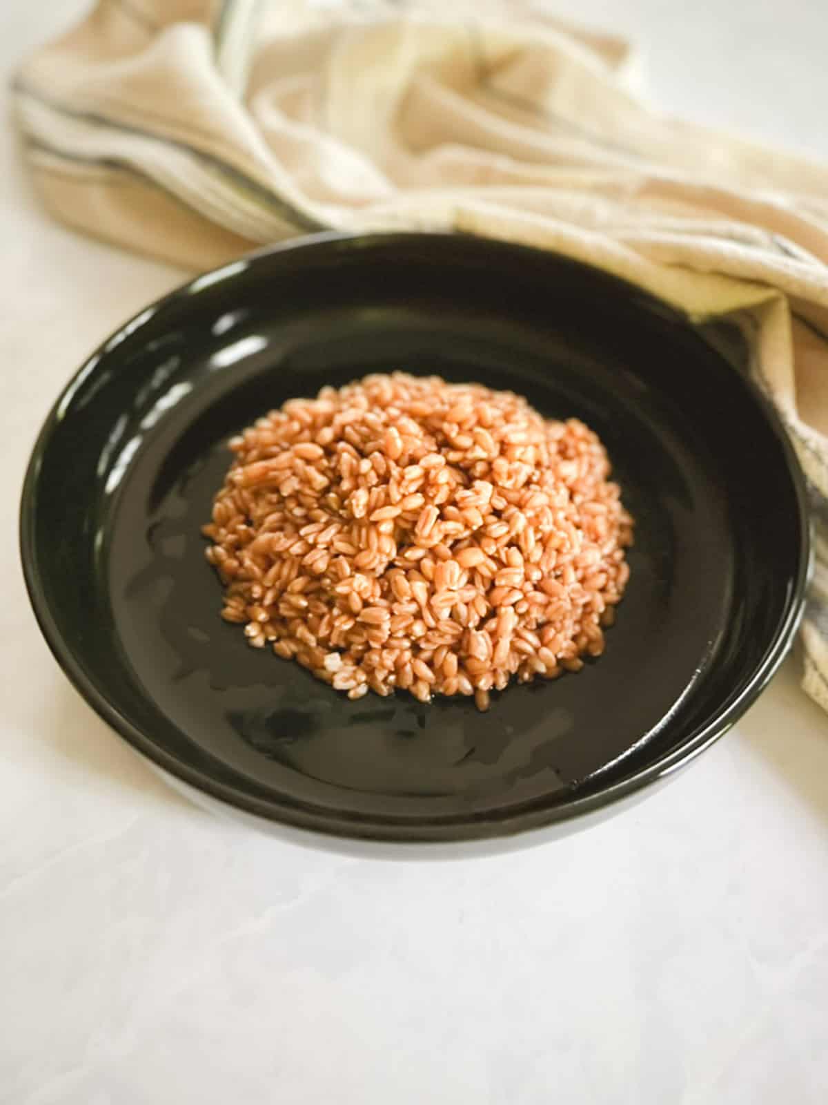 plate of cooked farro with a towel in the background