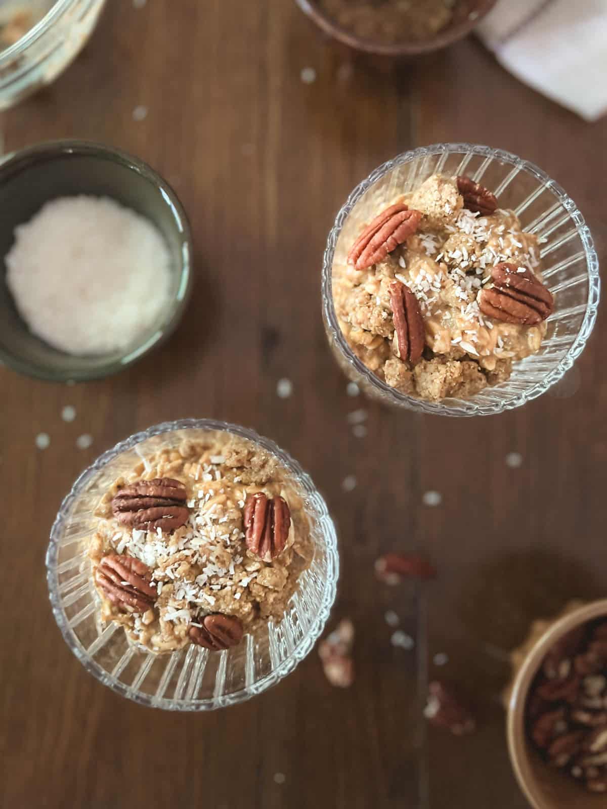 overhead of two parfait dishes of pumpkin spice overnight oats (without yogurt) with bowl of shredded coconut