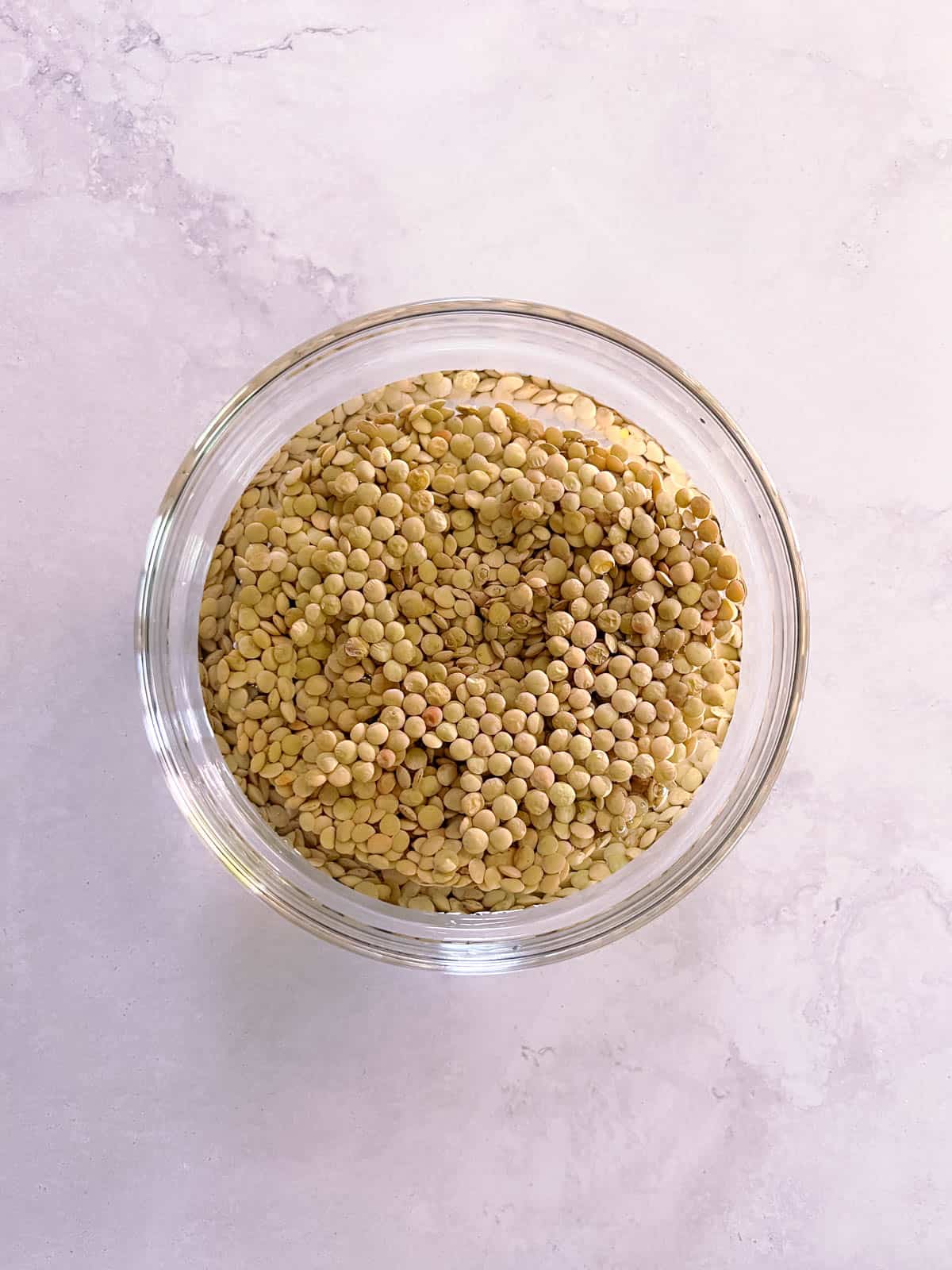 overhead of bowl of lentils soaking in water