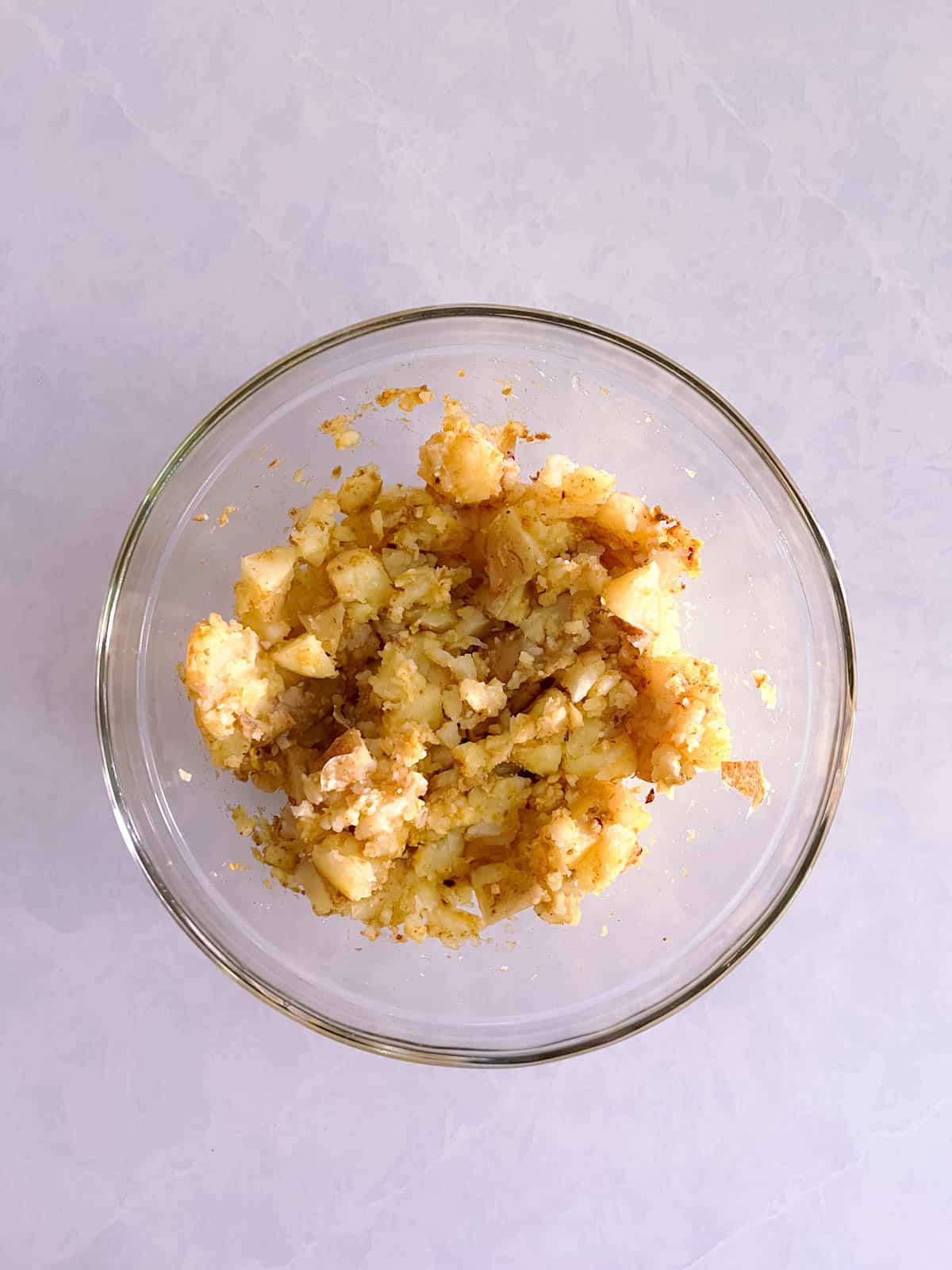 bowl of cooked potatoes and spices partially mashed