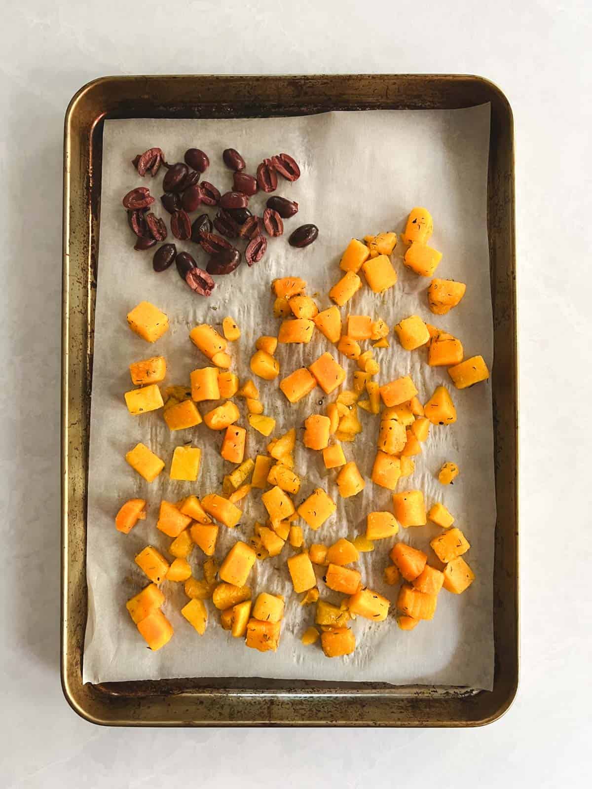 butternut squash and olives spread on prepared baking sheet