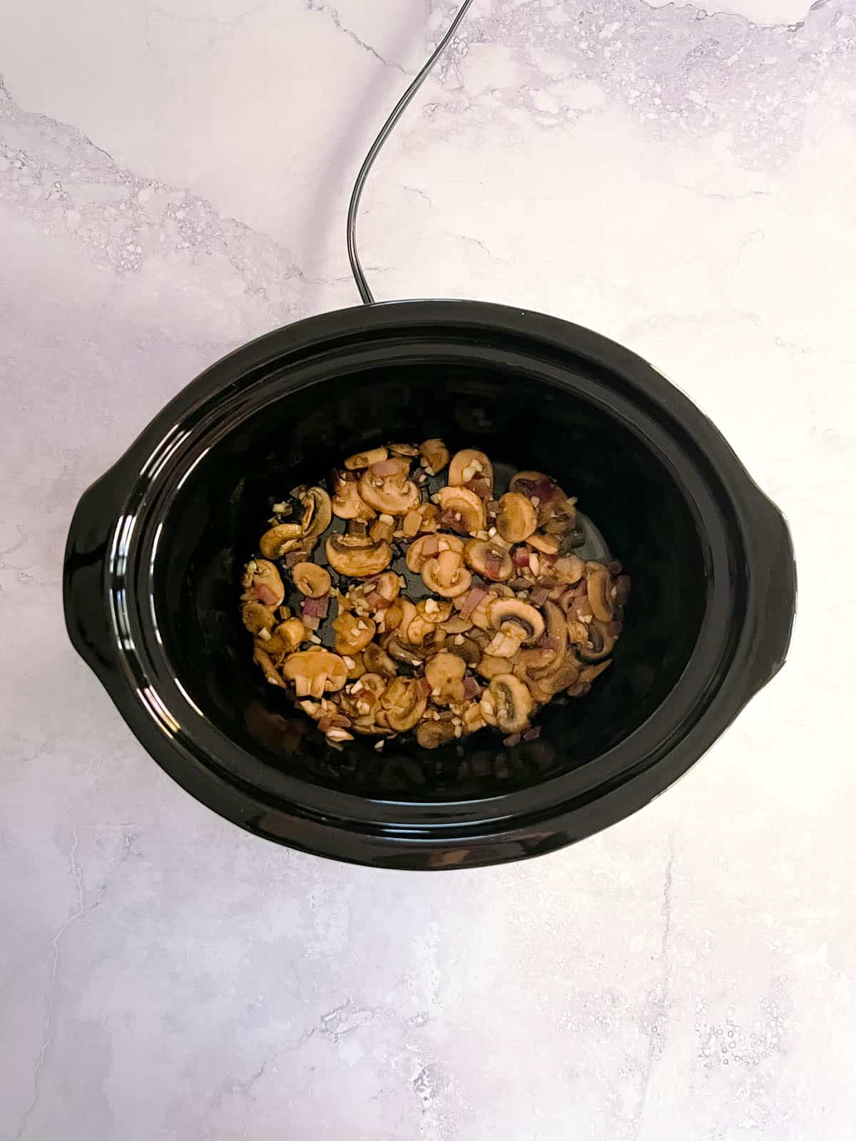 slow cooker containing mixture of cooked mushrooms, onions, and garlic