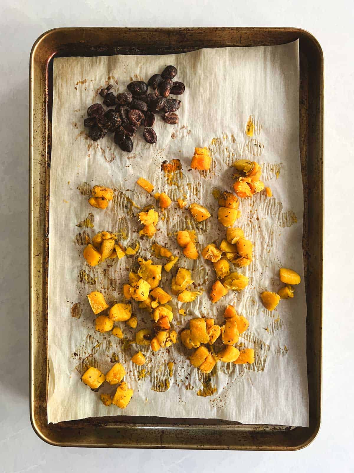 roasted butternut squash and olives on a baking sheet