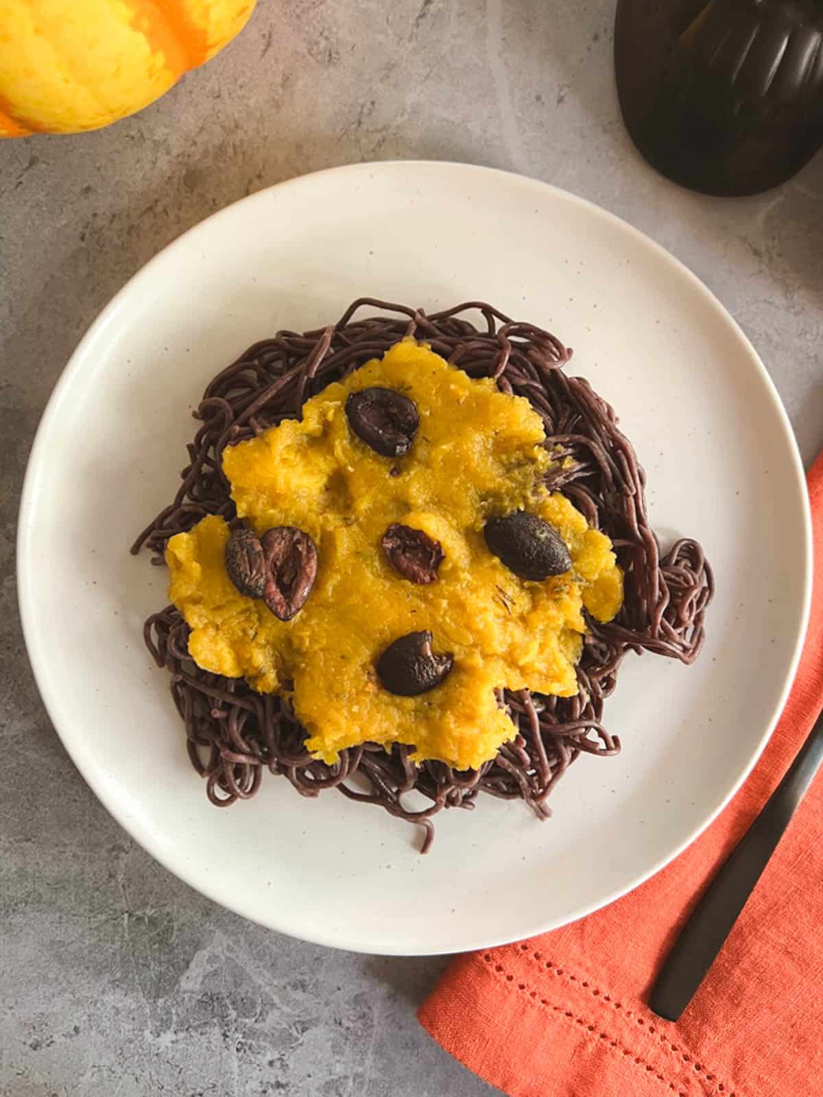 overhead view of a serving of vegan Halloween pasta garnished with roasted olives