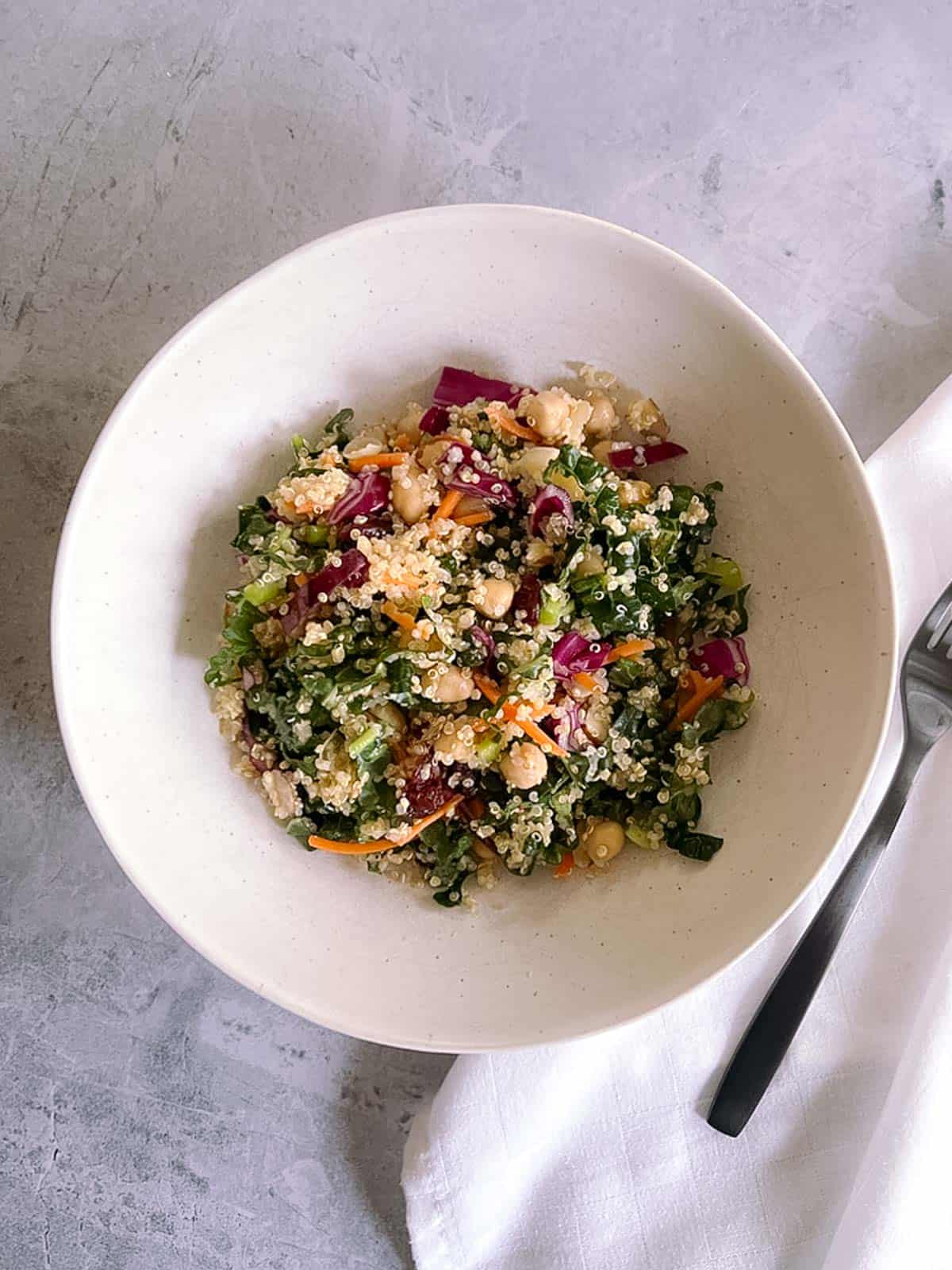 overhead view of a bowl of autumn quinoa salad with a fork and napkin