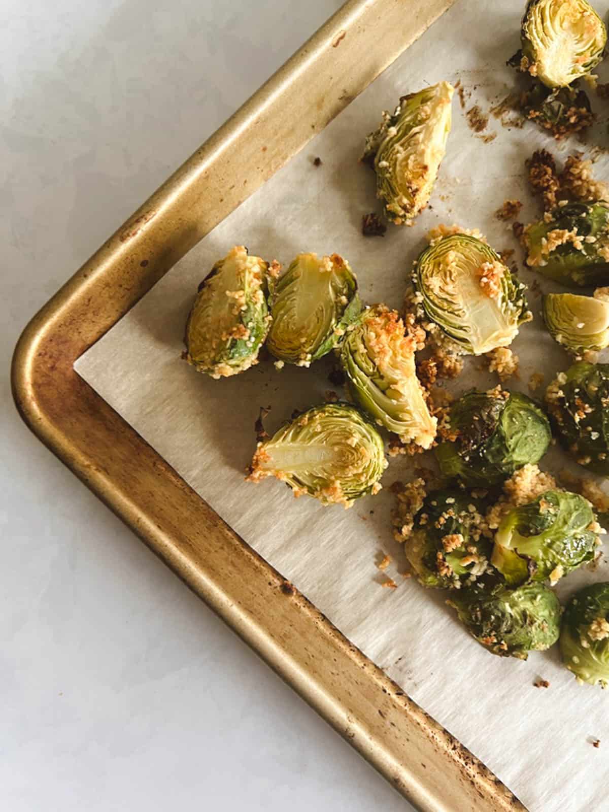 close up of corner of baking sheet with roasted crispy brussels sprouts