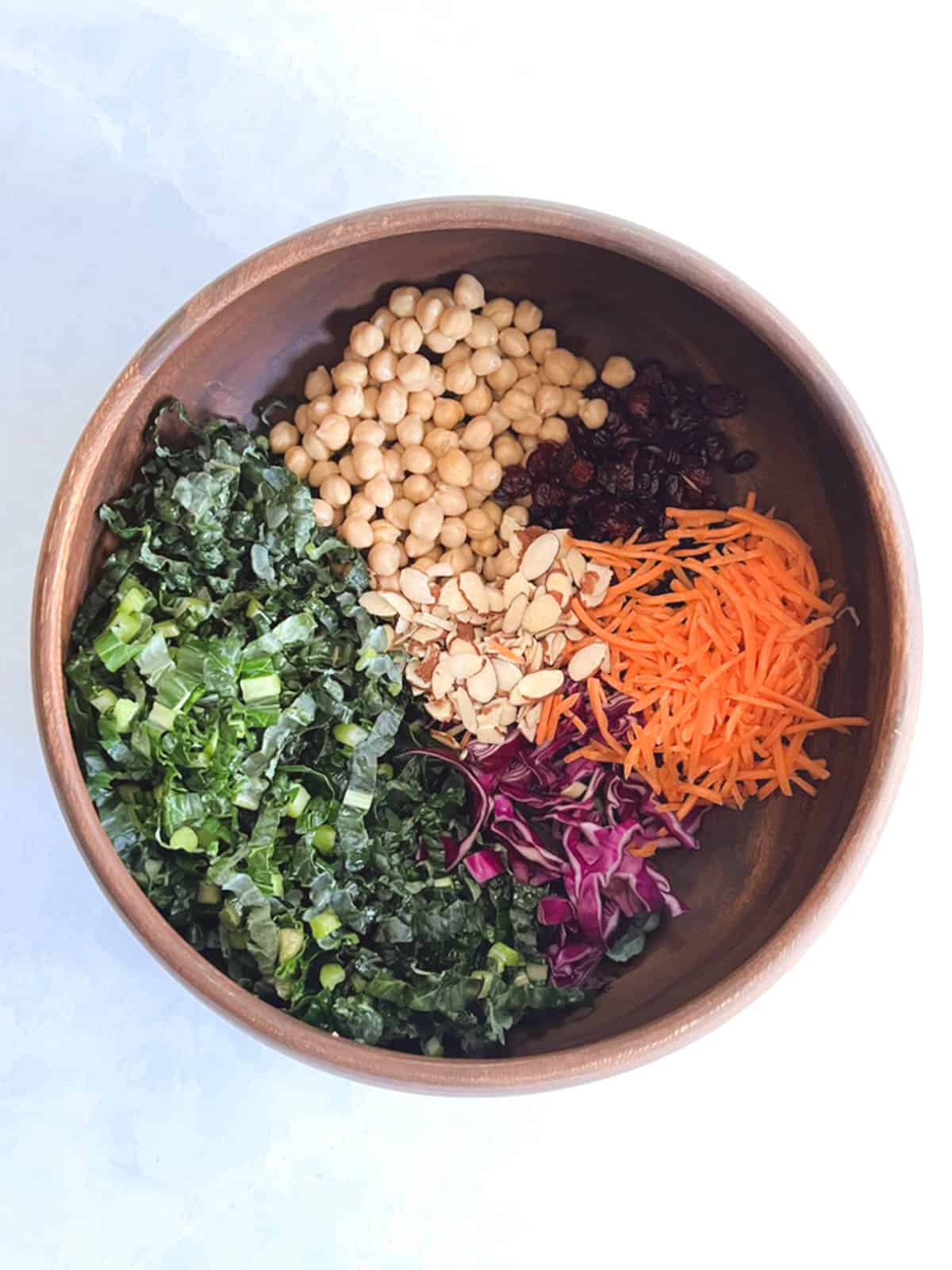 overhead of large wooden bowl containing unmixed ingredients for autumn quinoa salad